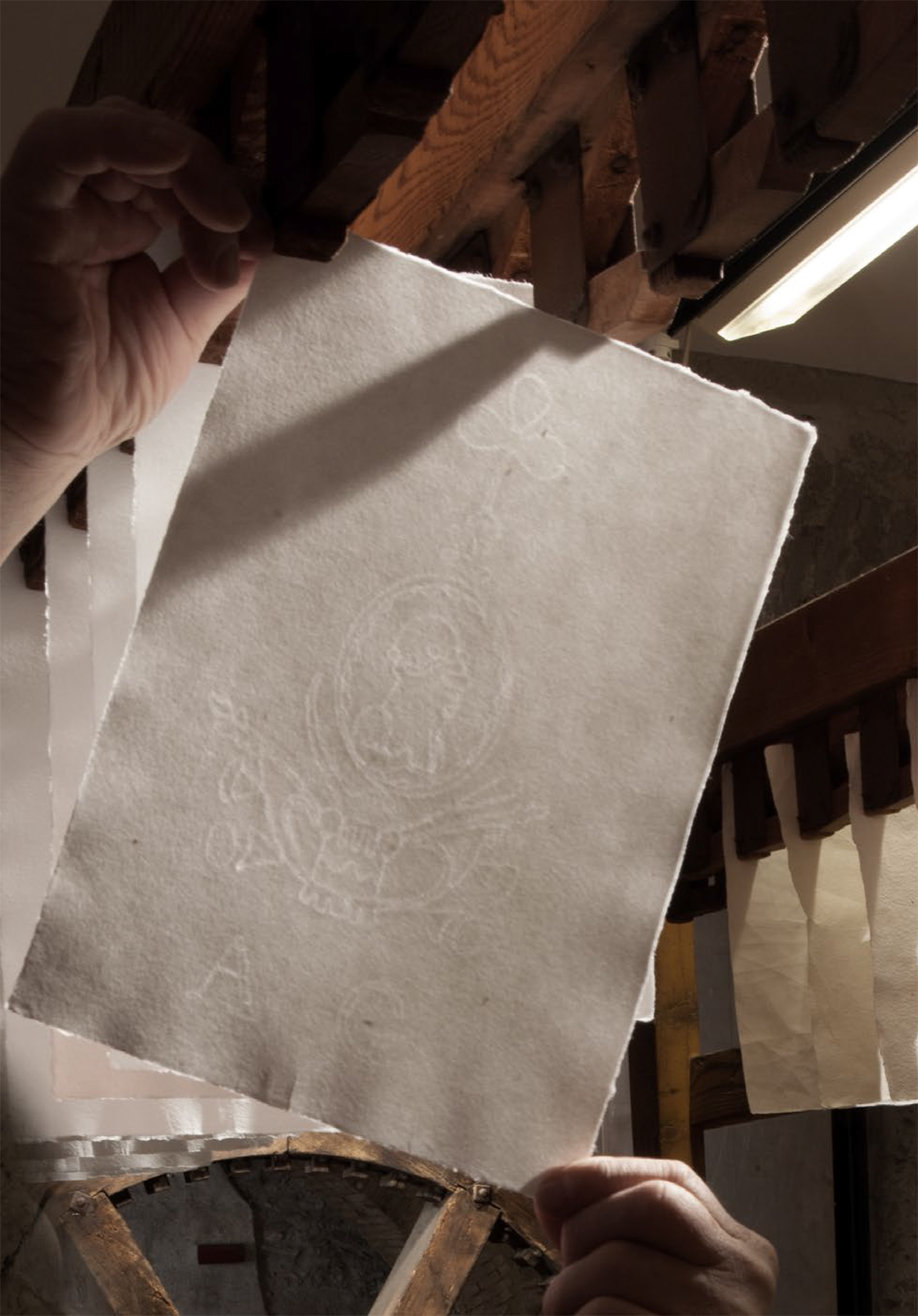 Foglio di carta steso ad asciugare sullo stenditoio, dove si può vedere bene la filigrana Giustacchini. Toscolano maderno, Ecomuseo della Valle delle Cartiere